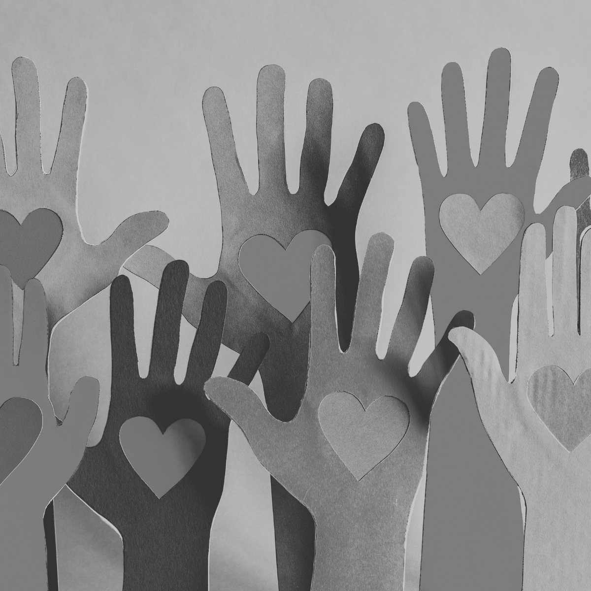 paper hands raised with hearts in them in black and white
